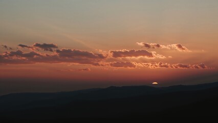 Silhouetted hills beneath a glowing evening sky