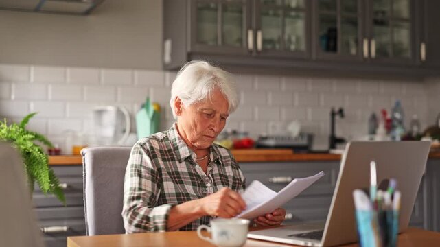 Senior woman looking through financial documents at home
