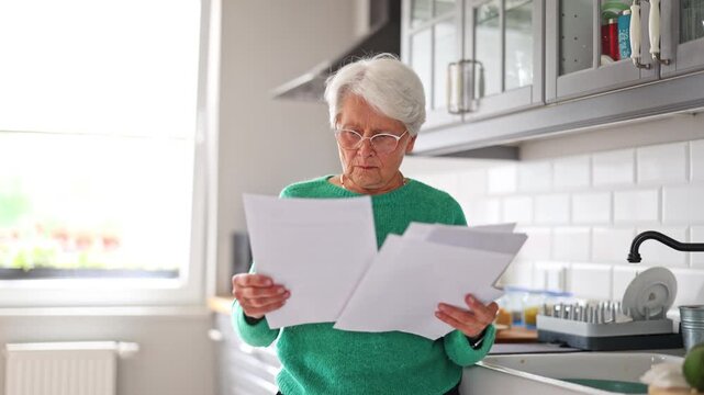 Senior woman looking through financial documents at home
