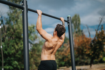 Fit athlete exercising with pull-ups on an outdoor bar in a lush park setting, showcasing strength and dedication towards fitness in the open air.