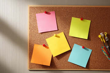 Multiple colorful sticky notes pinned on cork bulletin board with soft shadows. Perfect for message reminders or creative planning. Copy space included.