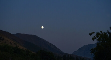In the evening, the moon is visible above the mountain