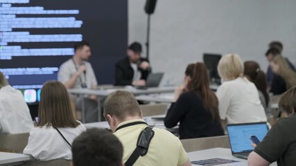 Attendees at a professional workshop listen to a speaker discussing technology-related topics and collaboration.