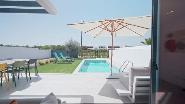 Luxurious villa showcasing modern interior design, open plan living area, and private swimming pool with sun loungers and garden furniture, creating a relaxing and inviting atmosphere