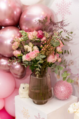 Elegant floral arrangement in a glass vase surrounded by pink and gold balloons at a celebration