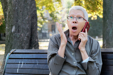 Elderly person expressing surprise while talking on the phone in a park during autumn
