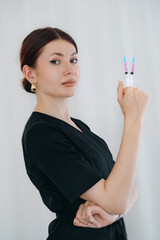young woman aesthetician doctor wearing black medical suit holding syringes