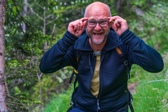 Happy Man with glasses and a black jacket and backpack along to the Bavarian hiking paths