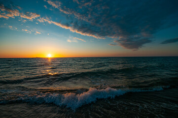 Beautiful colorful sunset in cloud sky at waving sea