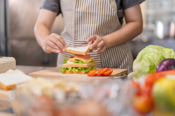 Hands placing final slice of bread on a sandwich.
