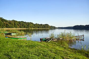 Obraz premium Old, dilapidated fishing pier and boat on the lake shore