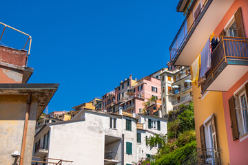 Italian shutters on the windows balcony of pink orange color house. Open wooden shutter in summer. Architecture building. Cinque Terre blue cky