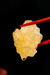 Handmade ancient yellow icing sugar large cubes displayed delicately with chopsticks against a dark background