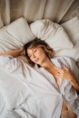 Obraz premium sexy woman in white shirt in bed. female attractiveness and sexuality. top view