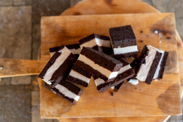 Delicious chocolate dessert squares with creamy filling on a wooden cutting board