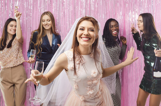 Bachelorette party celebrating, bride and women friends posing smiling, wearing white veil and dress, holding champagne glasses, bottle drink, joyful fun, happiness and friendship, dancing joy