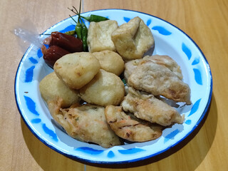 Gorengan, traditional Indonesian street food consisting of brontak tofu, fried banana, bakwan, jemblem, etc. Served with green chilies.