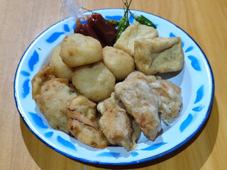 Gorengan, traditional Indonesian street food consisting of brontak tofu, fried banana, bakwan, jemblem, etc. Served with green chilies.