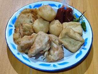 Gorengan, traditional Indonesian street food consisting of brontak tofu, fried banana, bakwan, jemblem, etc. Served with green chilies.