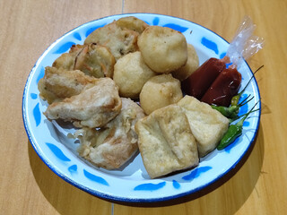 Gorengan, traditional Indonesian street food consisting of brontak tofu, fried banana, bakwan, jemblem, etc. Served with green chilies.