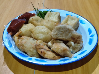 Gorengan, traditional Indonesian street food consisting of brontak tofu, fried banana, bakwan, jemblem, etc. Served with green chilies.