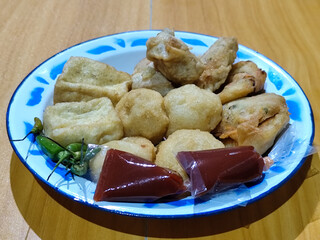 Gorengan, traditional Indonesian street food consisting of brontak tofu, fried banana, bakwan, jemblem, etc. Served with green chilies.
