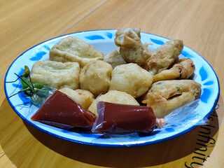 Gorengan, traditional Indonesian street food consisting of brontak tofu, fried banana, bakwan, jemblem, etc. Served with green chilies.
