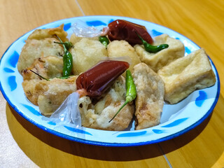 Gorengan, traditional Indonesian street food consisting of brontak tofu, fried banana, bakwan, jemblem, etc. Served with green chilies.