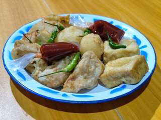 Gorengan, traditional Indonesian street food consisting of brontak tofu, fried banana, bakwan, jemblem, etc. Served with green chilies.