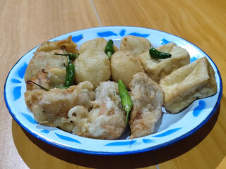 Gorengan, traditional Indonesian street food consisting of brontak tofu, fried banana, bakwan, jemblem, etc. Served with green chilies.