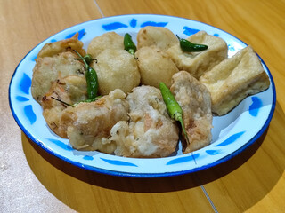 Gorengan, traditional Indonesian street food consisting of brontak tofu, fried banana, bakwan, jemblem, etc. Served with green chilies.
