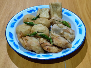 Gorengan, traditional Indonesian street food consisting of brontak tofu, fried banana, bakwan, jemblem, etc. Served with green chilies.