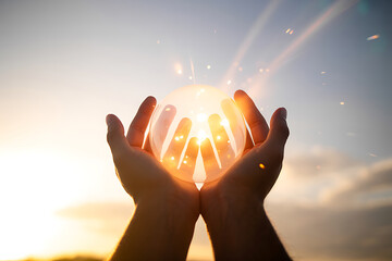 Hands cupping bright sunlight against a cloudy sky