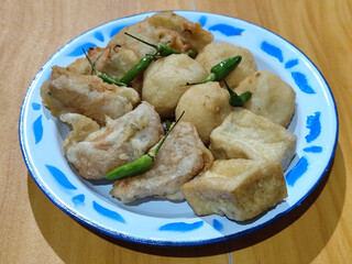 Gorengan, traditional Indonesian street food consisting of brontak tofu, fried banana, bakwan, jemblem, etc. Served with green chilies.