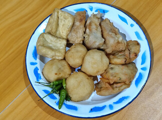 Gorengan, traditional Indonesian street food consisting of brontak tofu, fried banana, bakwan, jemblem, etc. Served with green chilies.