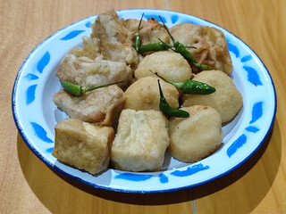 Gorengan, traditional Indonesian street food consisting of brontak tofu, fried banana, bakwan, jemblem, etc. Served with green chilies.