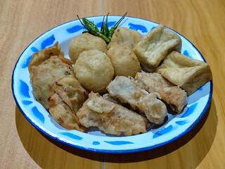 Gorengan, traditional Indonesian street food consisting of brontak tofu, fried banana, bakwan, jemblem, etc. Served with green chilies.