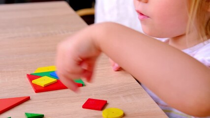 cute child, girl 3 years old plays with colored wooden geometric figures, counts details, concept of development of creativity, fine motor skills, patience perseverance, children's entertainment