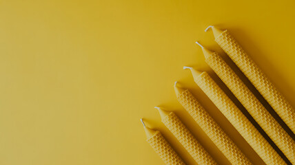 Aesthetic arrangement of natural beeswax candles on a yellow background