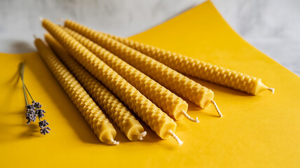 Aesthetic arrangement of natural beeswax candles on a yellow background