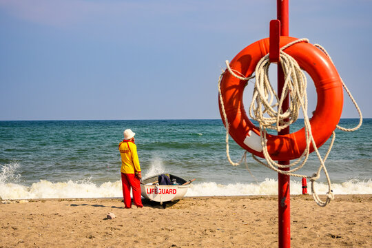 lifeguard with row boat and safety equipment on the beach as small waves break on sand room for text copy space shot kew beach toronto in july - Powered by Adobe
