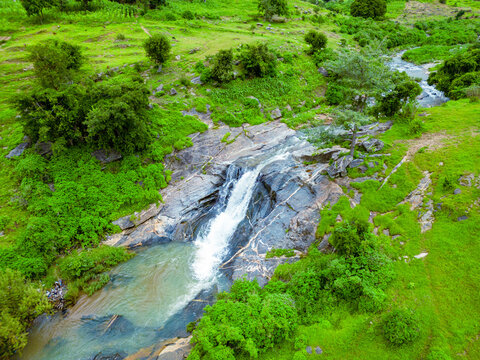 Aerial view of cascading waterfall over rugged rocks, embraced by verdant foliage, a symphony of nature's artistry, Maza village, Jos North, Nigeria.