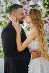 Beautiful and gentle bride and groom on the background of flowers in the decor.
