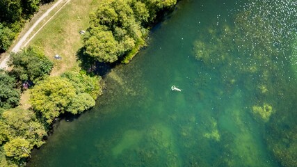 Aerial view of swimmer in clear green lake.