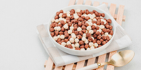 Vegan cereals in balls shape of cocoa and vanilla served with spoon. Full bowl ready to eat