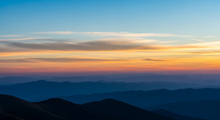 Fototapeta premium Layered mountain range silhouette at sunset with colorful sky gradient