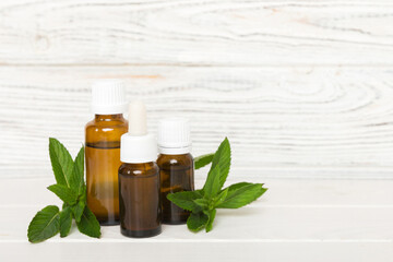 Natural Mint Essential Oil in a Glass Bottle. organic cosmetics with herbal extracts of mint on colored background