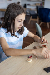 Young student assembling parts of educational project, learning through creative activity and improving practical skills at school.  Girl working on school craft and STEM project at desk
