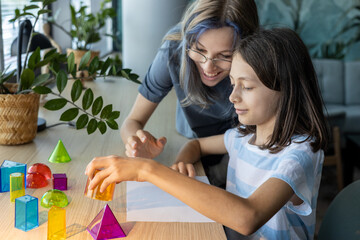 Two schoolgirls aged 11 and 13 working together on a STEM geometry project, exploring shapes and spatial concepts through hands-on learning and collaborative classroom activity.