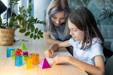 Two schoolgirls aged 11 and 13 working together on a STEM geometry project, exploring shapes and spatial concepts through hands-on learning and collaborative classroom activity.
